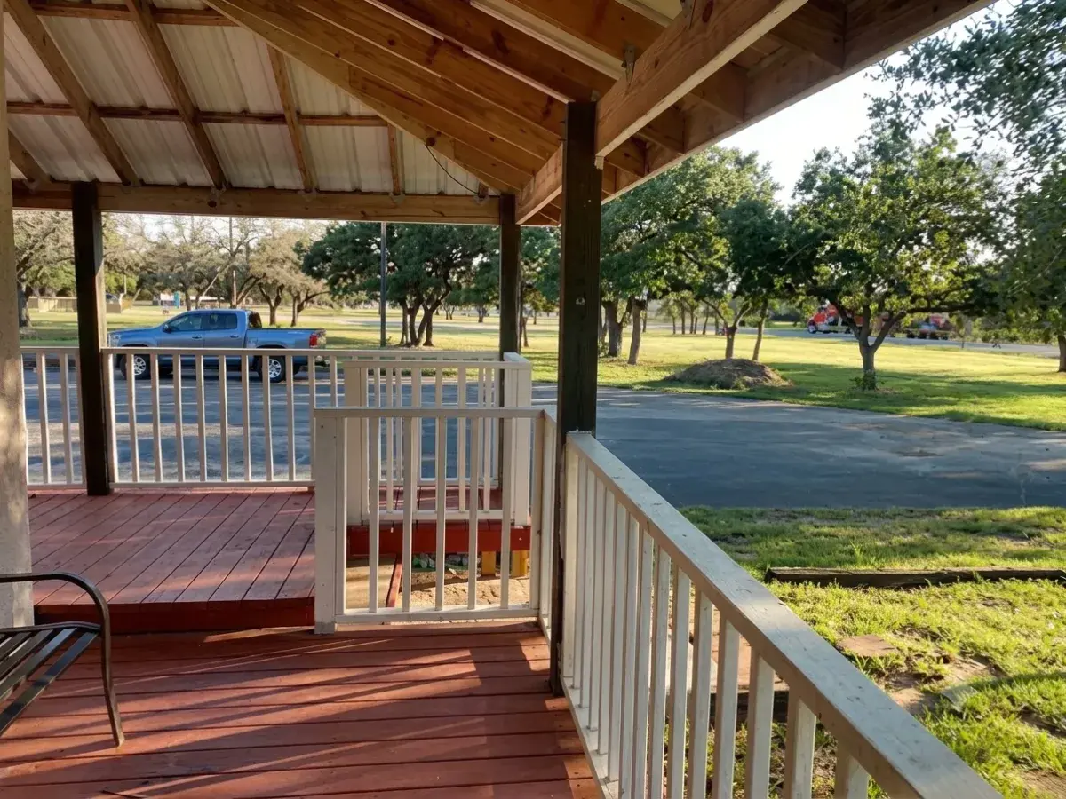 Covered porch with white railing looking out over the lawn at Outpost Motel